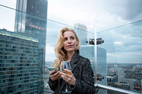 Woman checking her smartphone while drinking wine